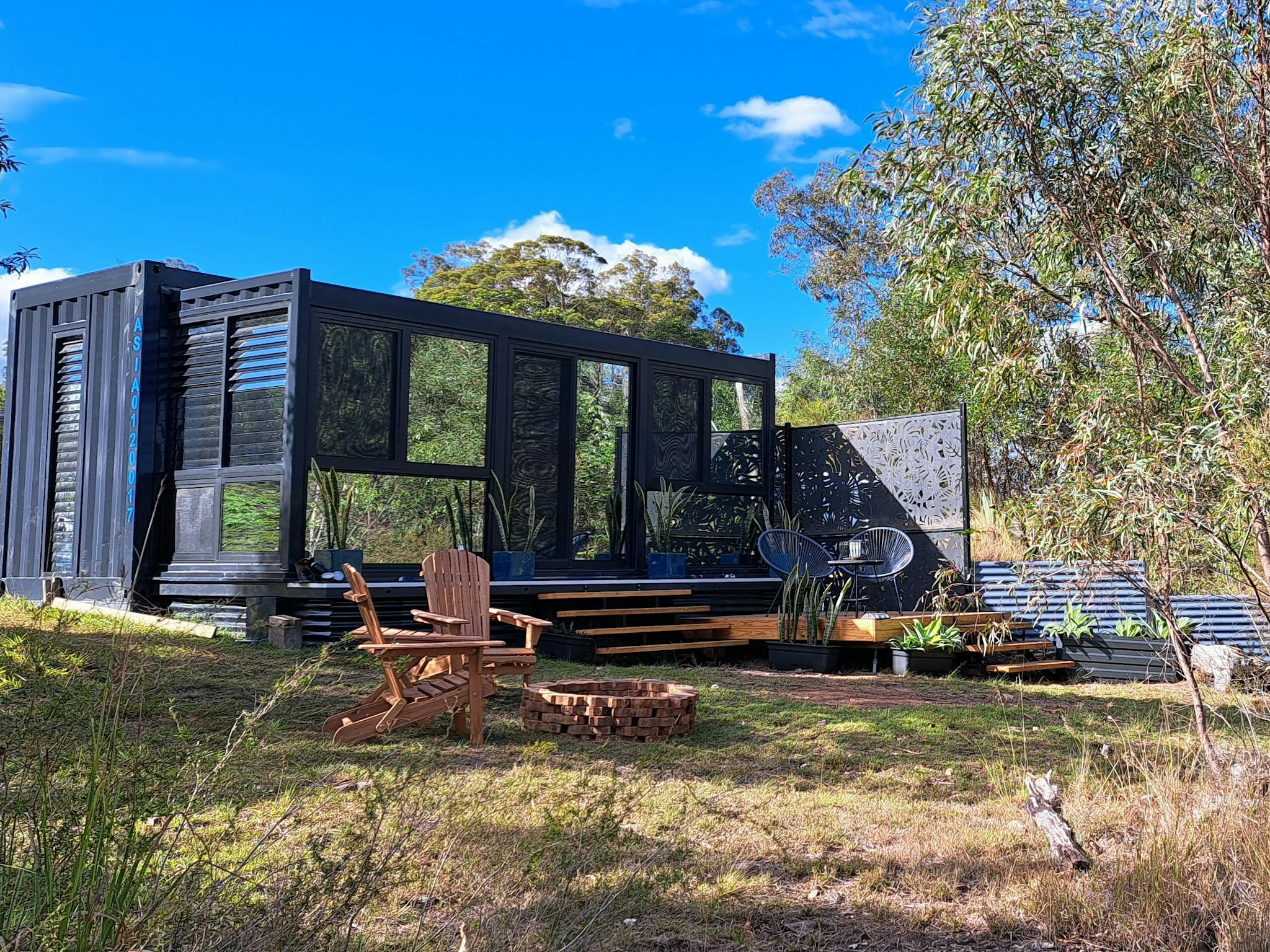 exterior view of container tiny home set in a bash setting surrounded by trees exterior view of container tiny home set in a bash setting surrounded by trees