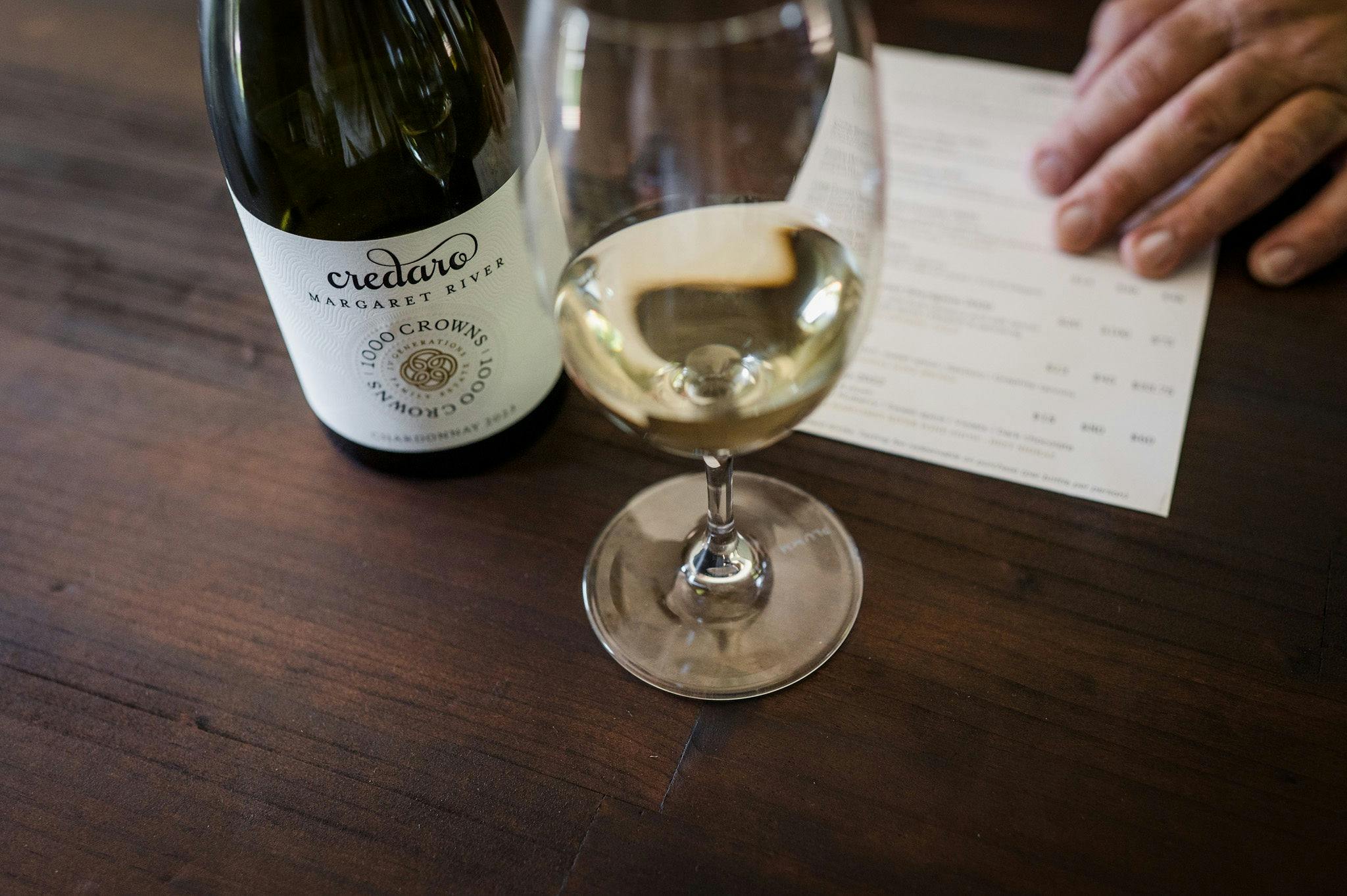 Credaro Estate 1000 Crowns Chardonnay bottle & wine glass with tasting menu in foreground