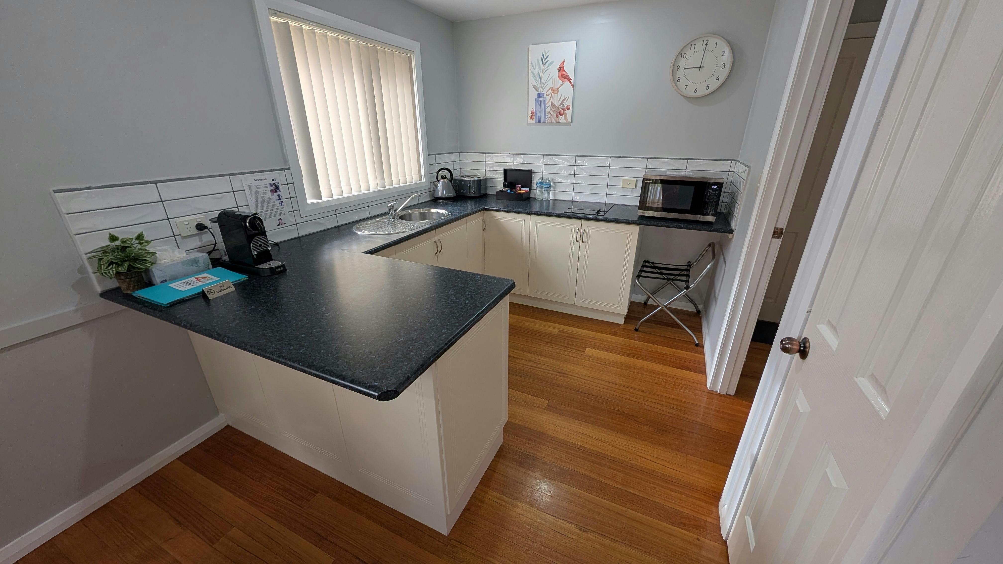 Full kitchen with breakfast bar, timber floors, microwave, sink and coffee machine.