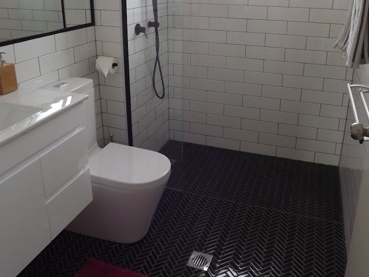 Rear to wall toilet, Floating vanity, White subway tiles with grey grout and Heringbone black floor