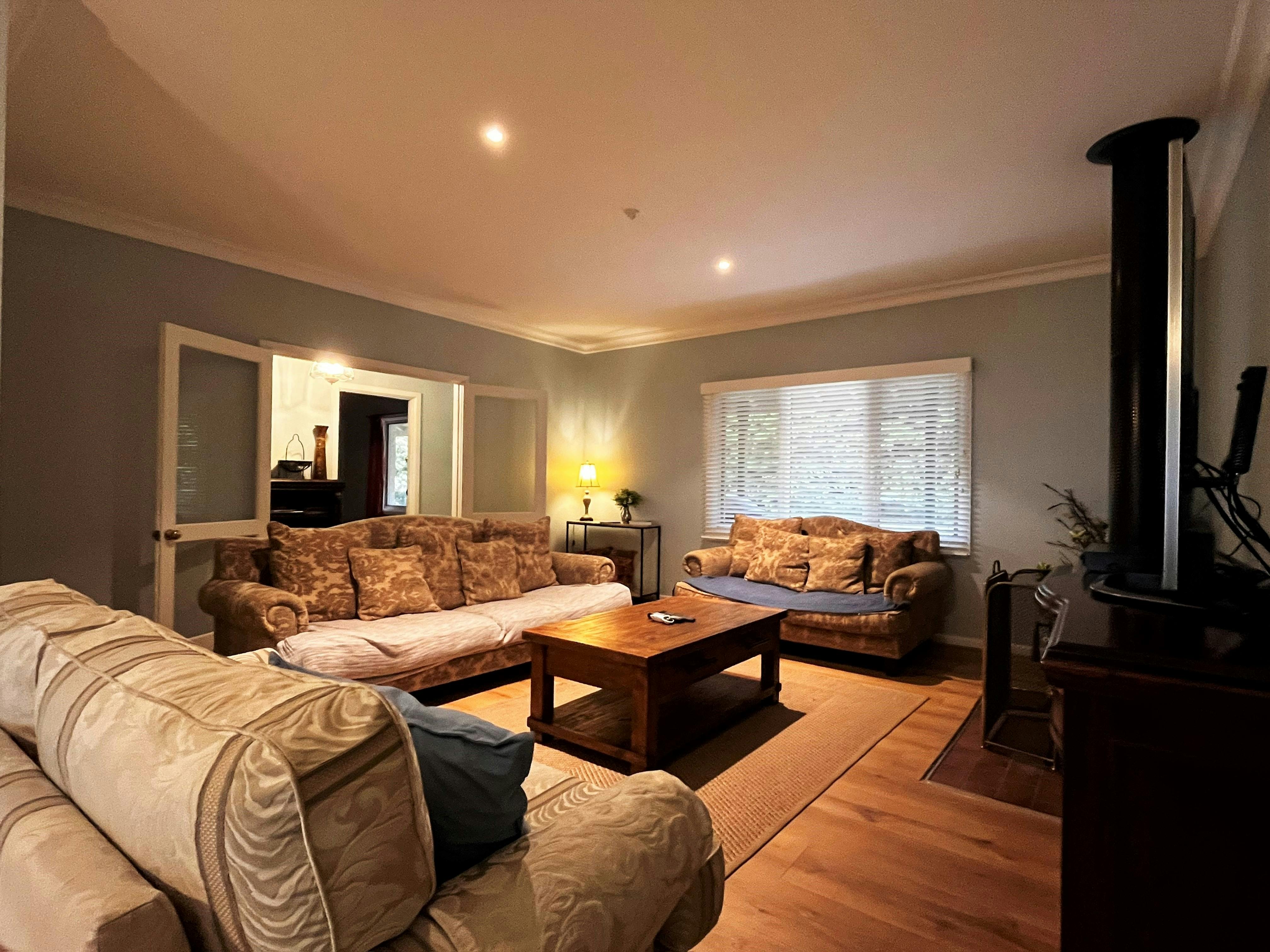 A cozy living room with plush sofas, warm lighting, and a wood heater, creating a perfect retreat.