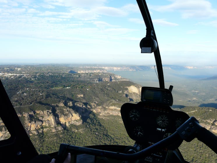 Cockpit view shot from inside helicopter looking out at Blue Mountains cliffs and escarpments