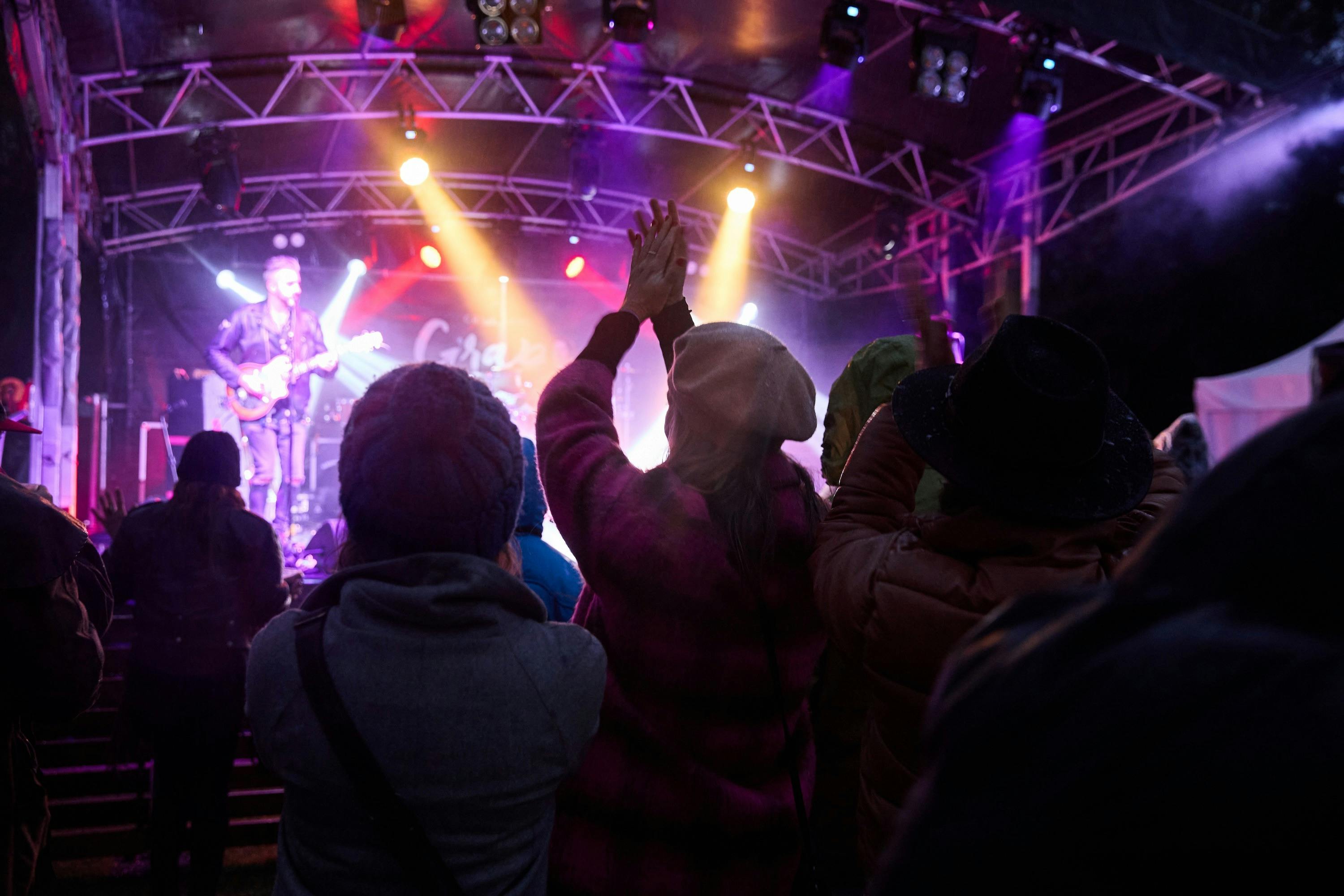 People watching a band play at Feel-Good Friday at Grampians Grape Escape at night with a light show