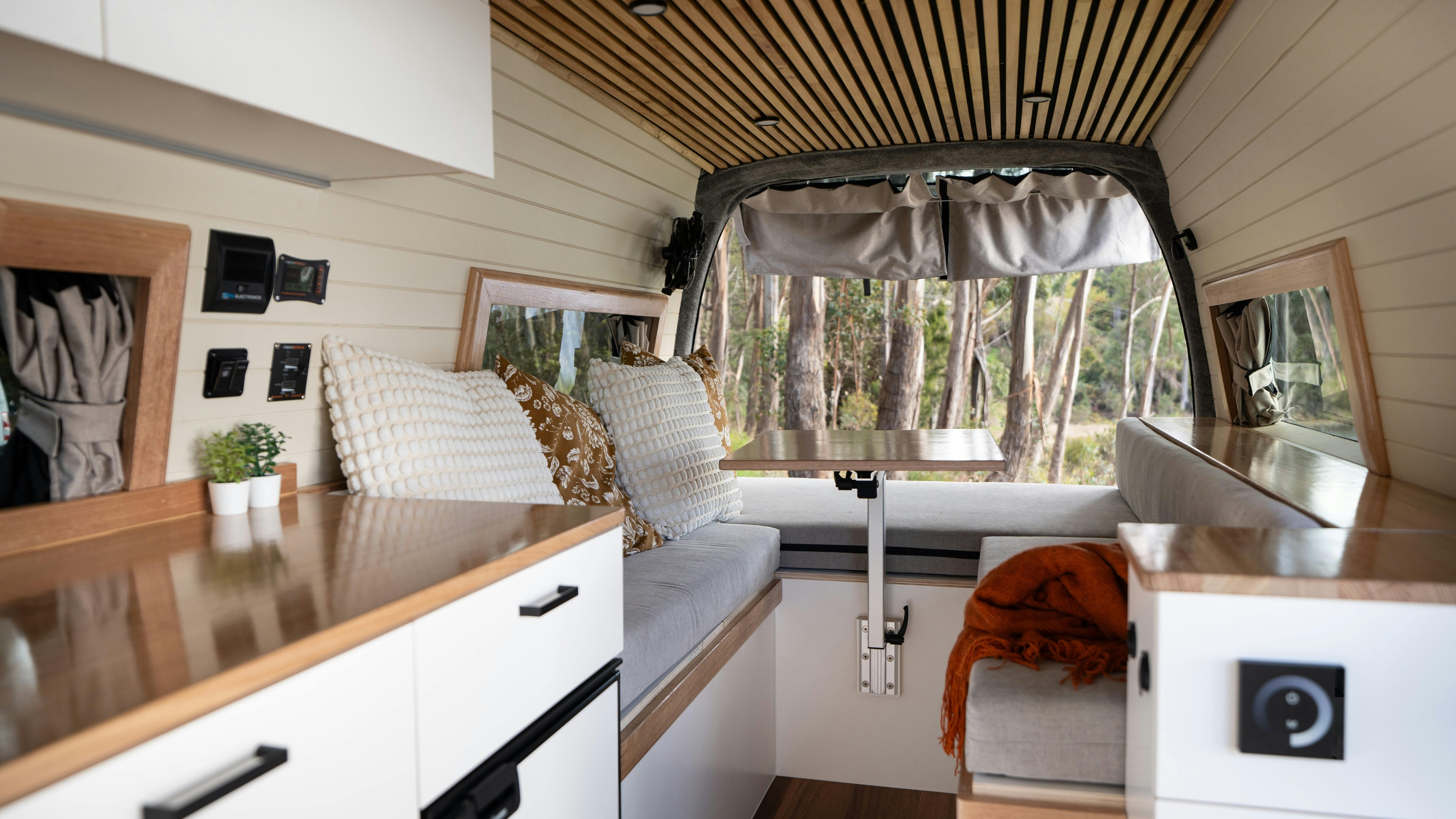 Premium campervan interior showcasing lounge seating and detailed wood craftsmanship.