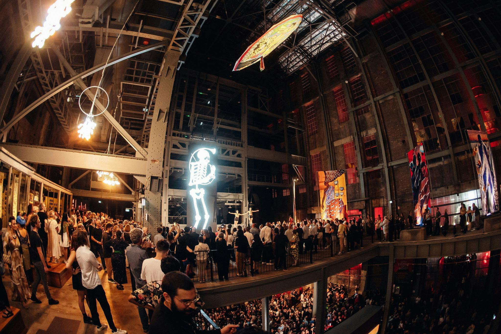 a large gathering of people surrounded by artwork in the boiler house of a heritage power station