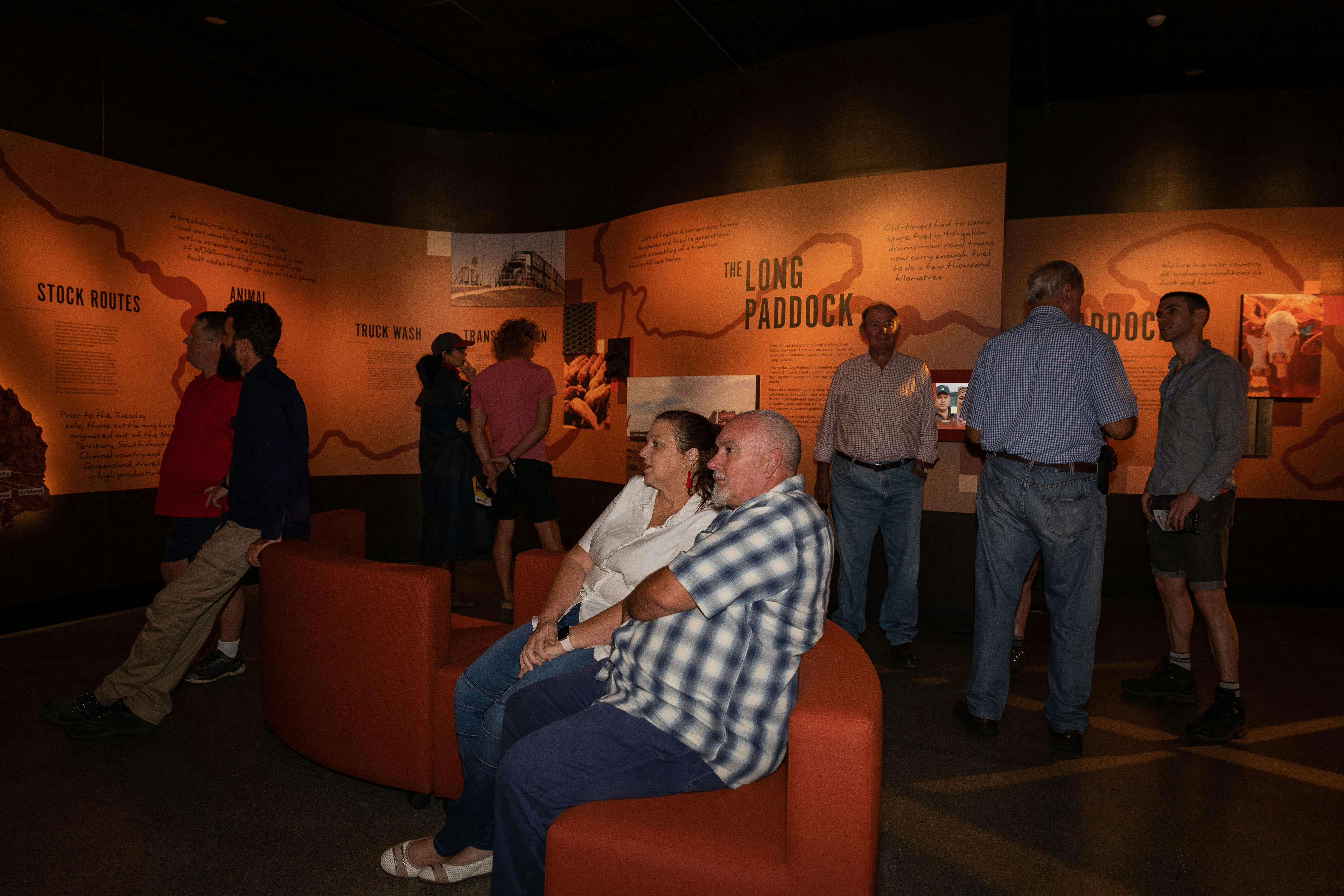 People sit on curved couches to view a screen (out of frame).