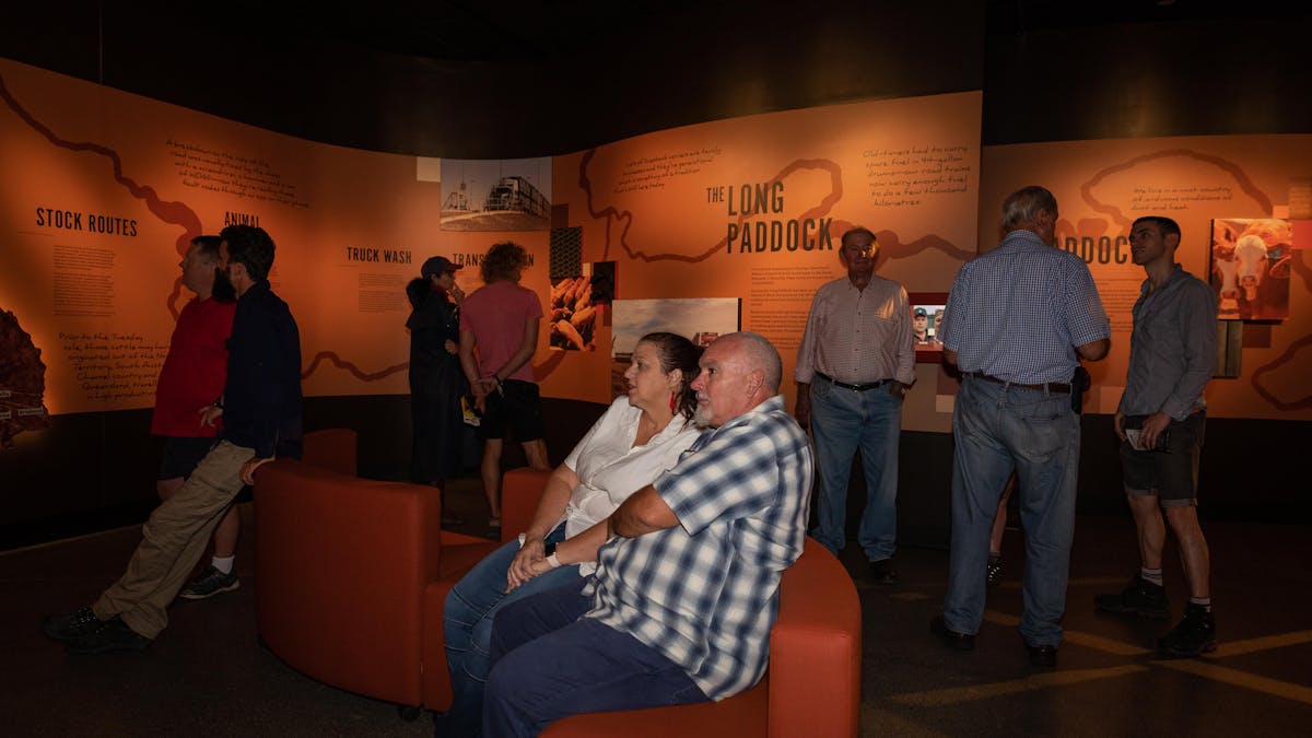 People sit on curved couches to view a screen (out of frame).