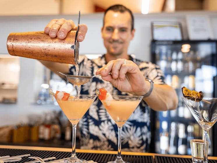 Barman pours fruit flavoured cocktails at the Oyster Shed bar
