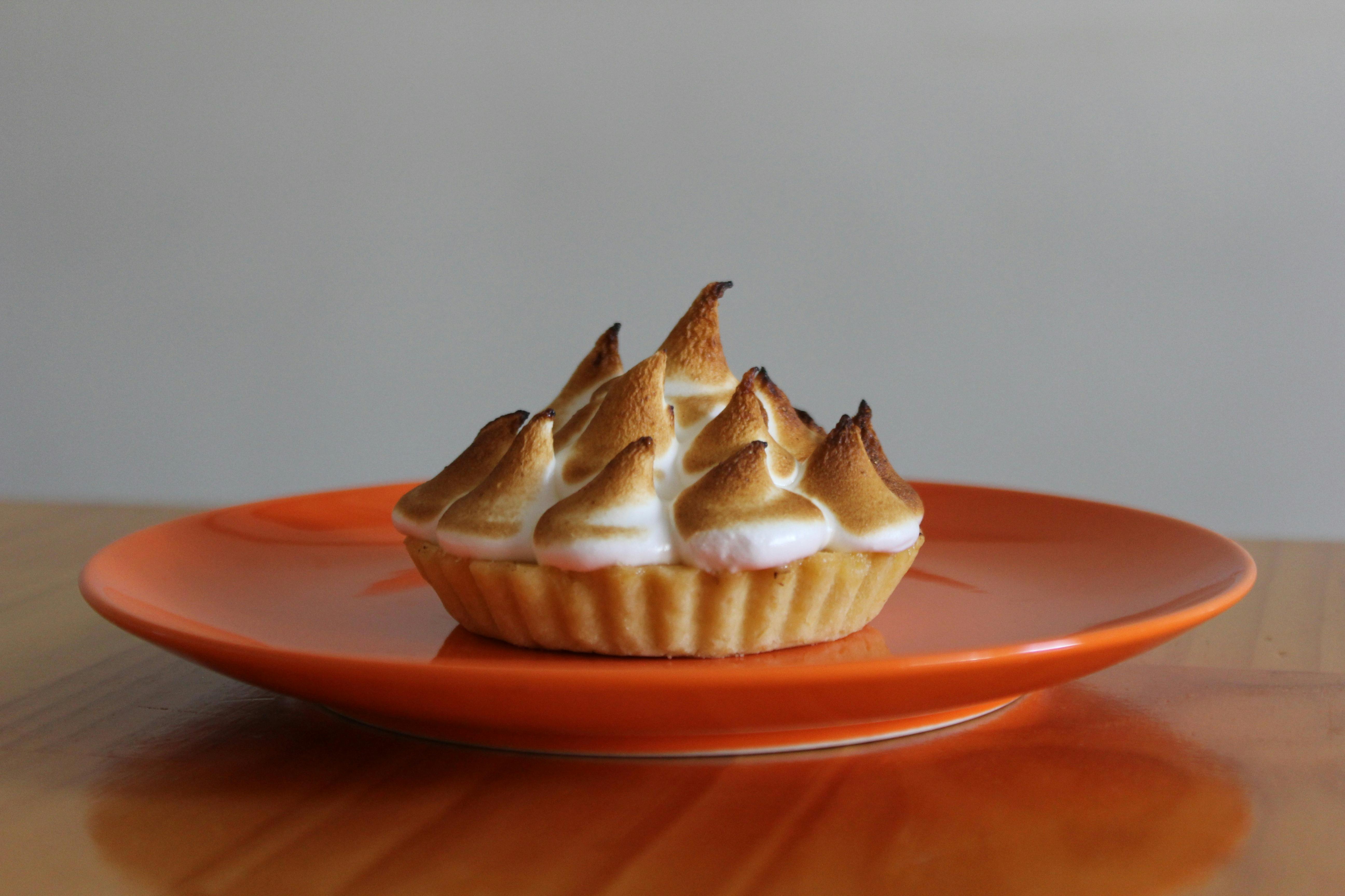 lemon Meringue tart on an orange plate in the Jacican cooking class kitchen