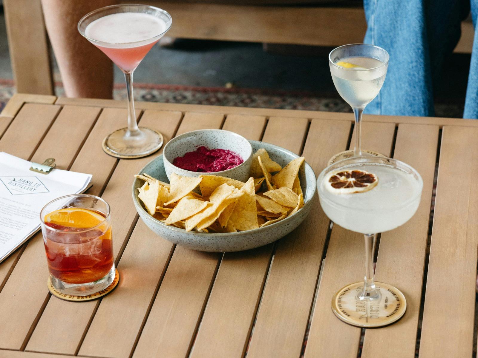 Cornchips and hummus bowl with four different types of cocktails