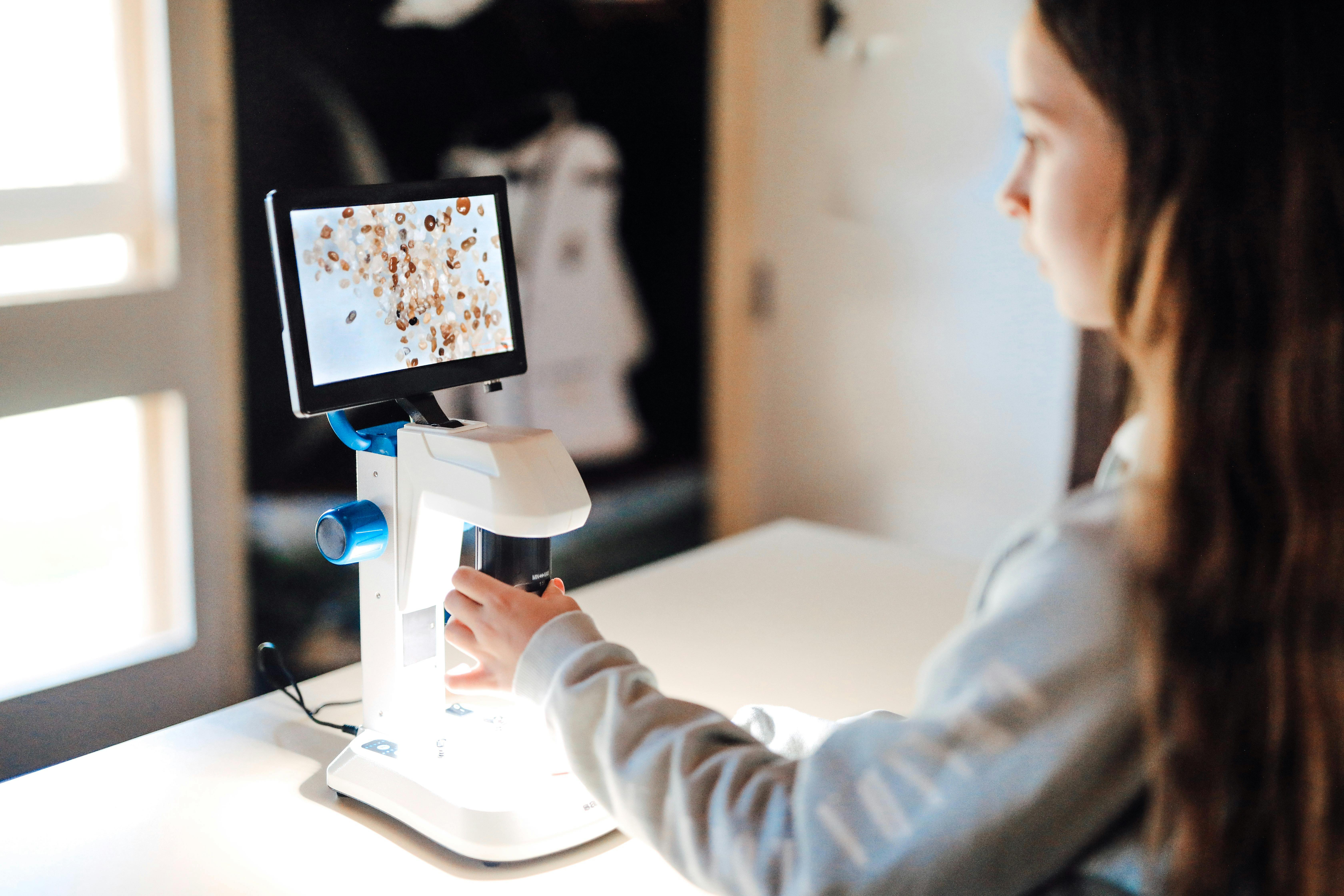 Girl looking at sand on the digital microscope