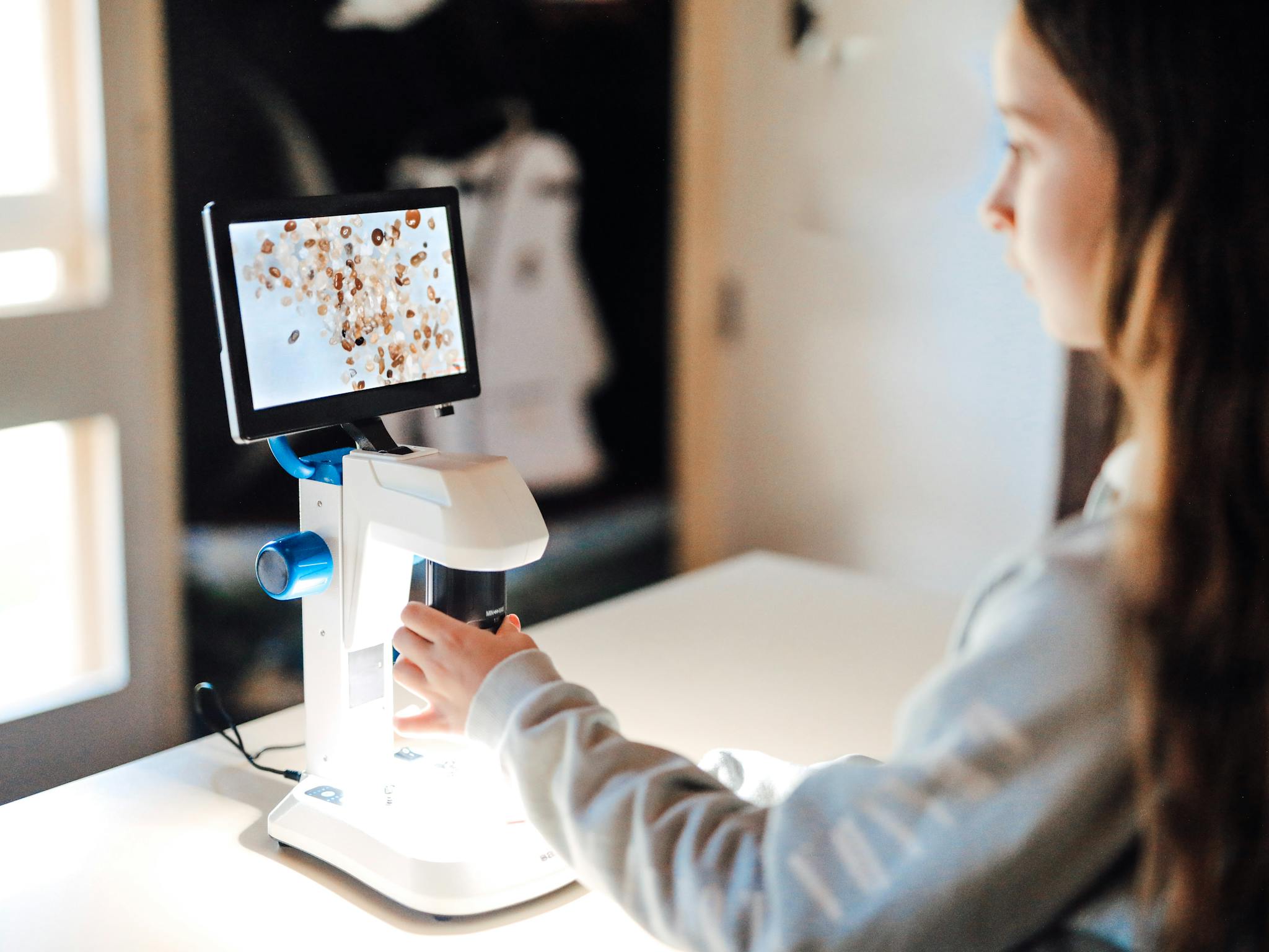 Girl looking at sand on the digital microscope