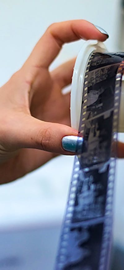 A photograph of a hand taking film off of a film reel