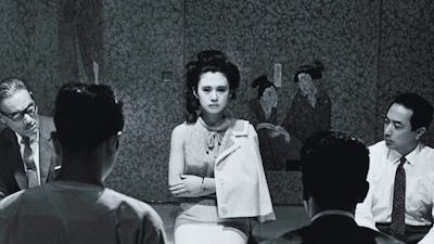 Black and white image of woman kneeling on floor with arms crossed