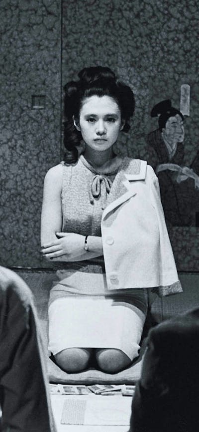 Black and white image of woman kneeling on floor with arms crossed