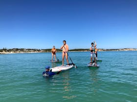 Sight impaired child being guided on the water by the coach who is holding the board in deep water