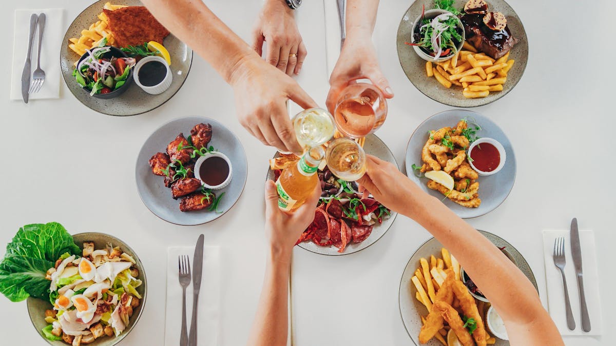 Cheersing glasses and plates of food