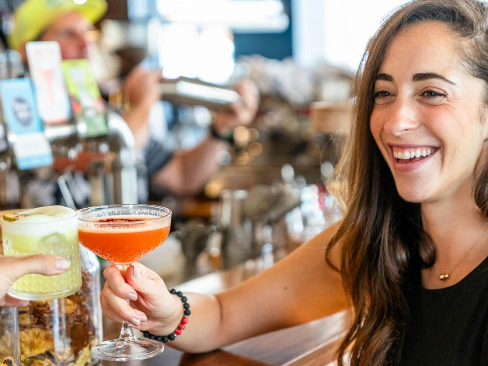 a woman cheersing a cocktail while sitting at the bar