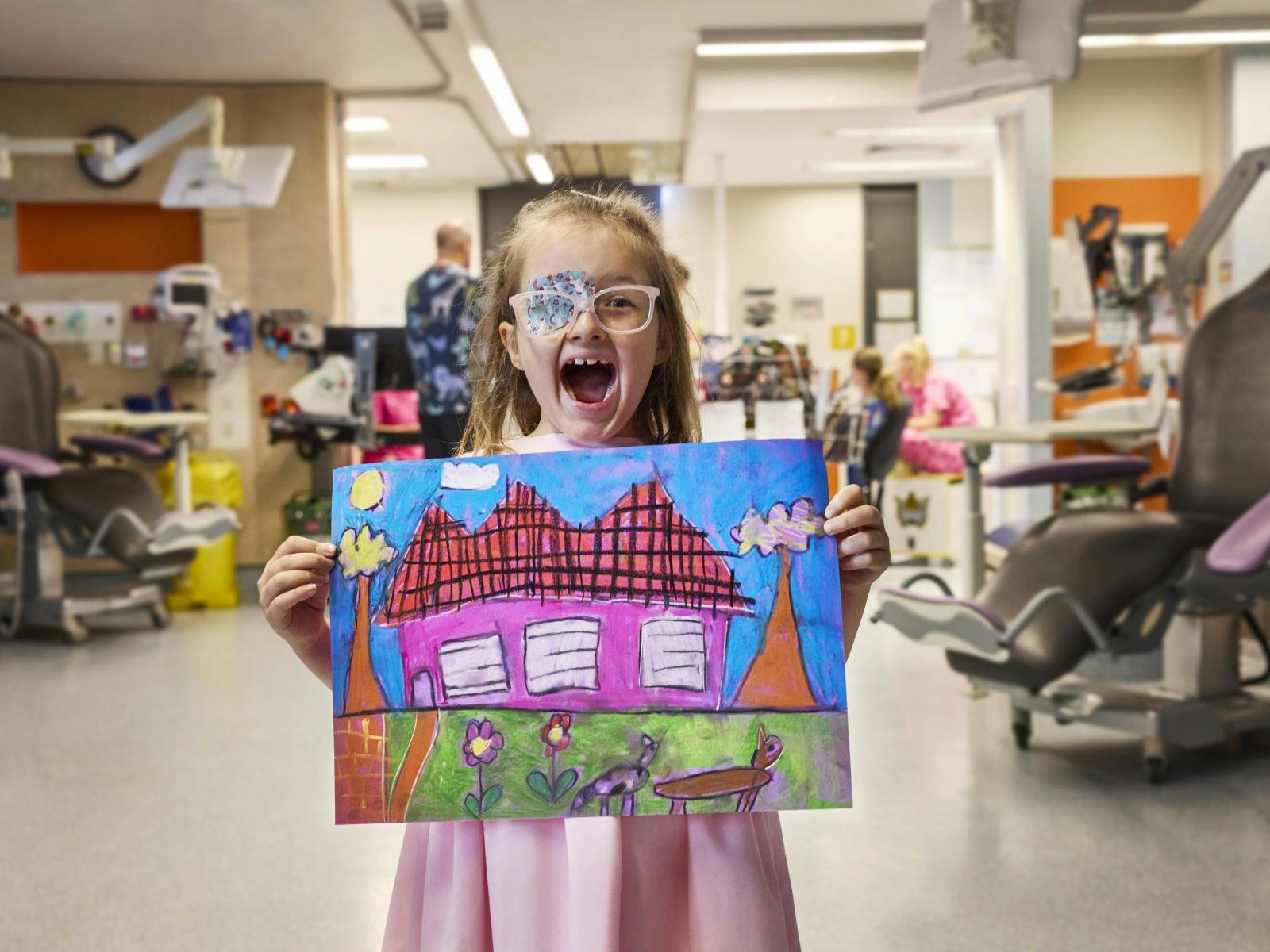 A child in hospital holding a drawing of a house A child in hospital holding a drawing of a house
