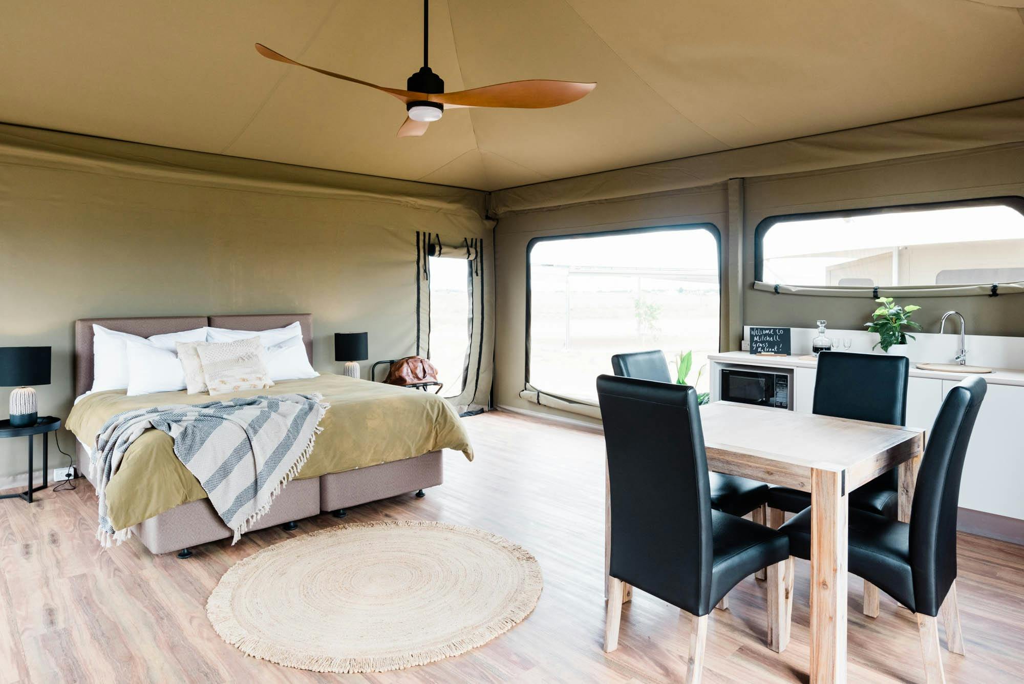 Large bed and dining table inside glamping tent