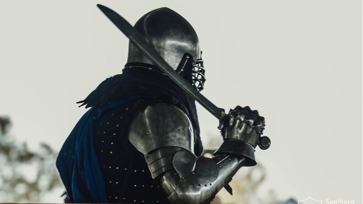 Armored Buhurt fighter holding a sword overhead at Southern Realm Festival.