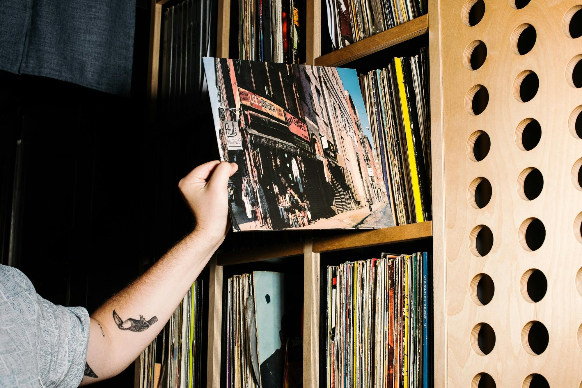 Hand nimmt Vinyl-Album aus dem Regal