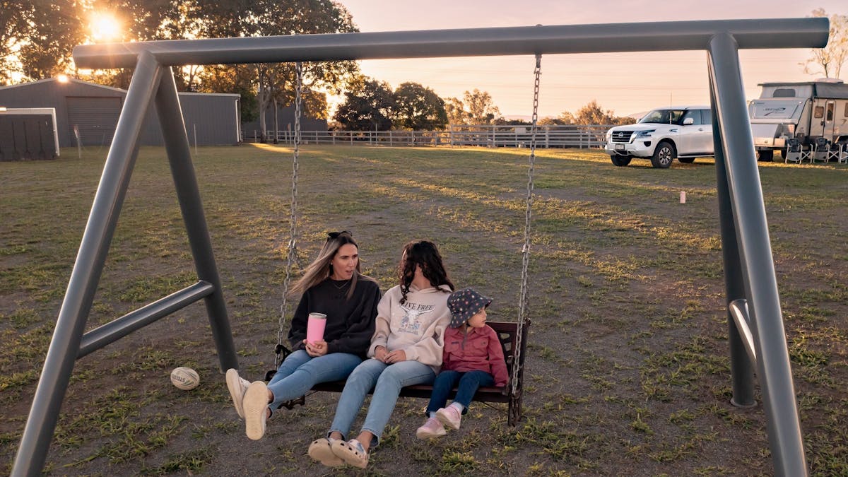Two adults and a child sitting in a swing on sunset in Mackay Region