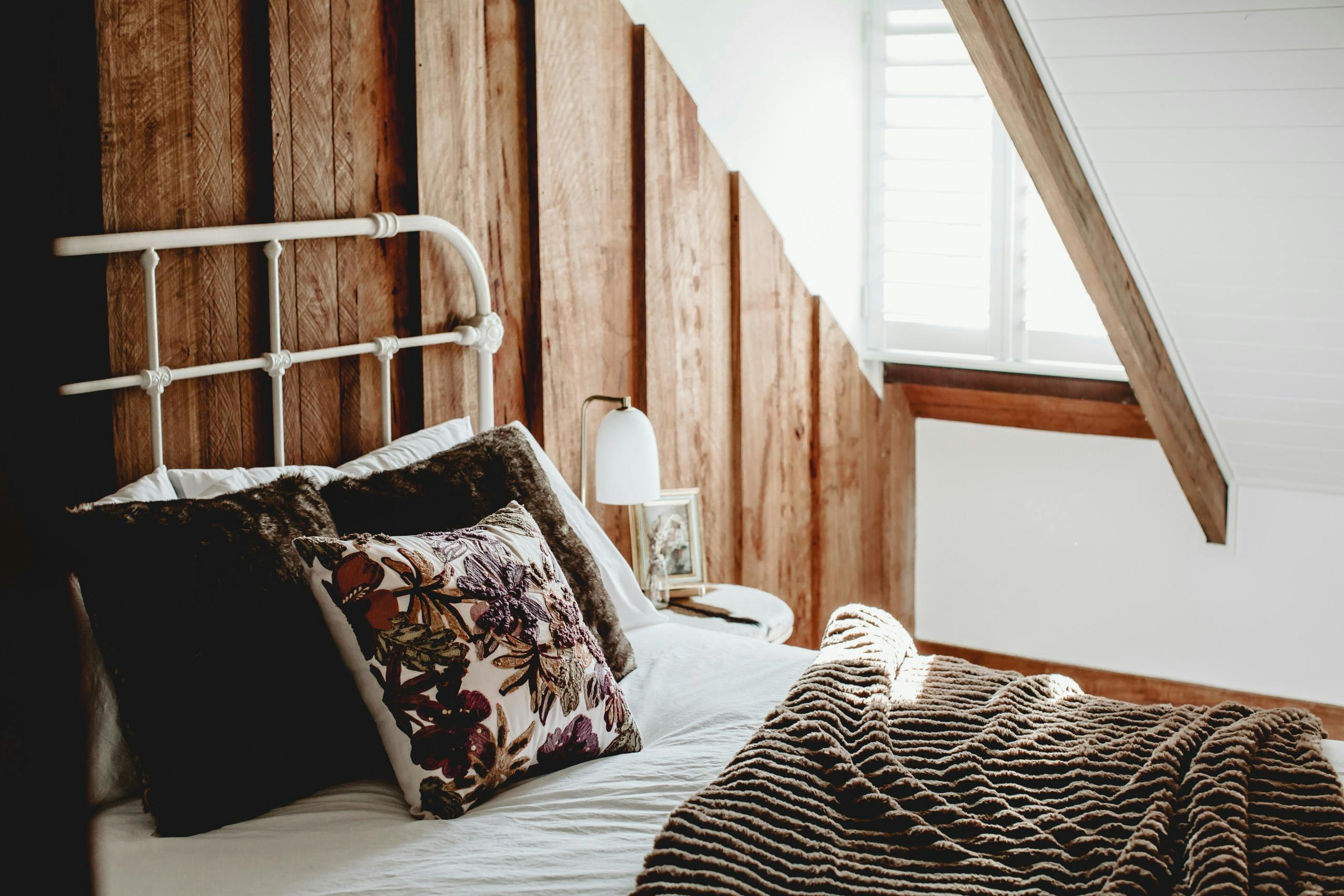 Warm inviting bed and angled window beside it.