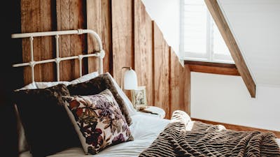 Warm inviting bed and angled window beside it.
