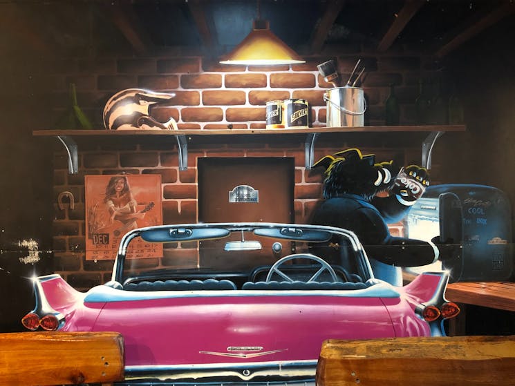 Wall poster with an animated boar driving a large, pink American style convertible car.