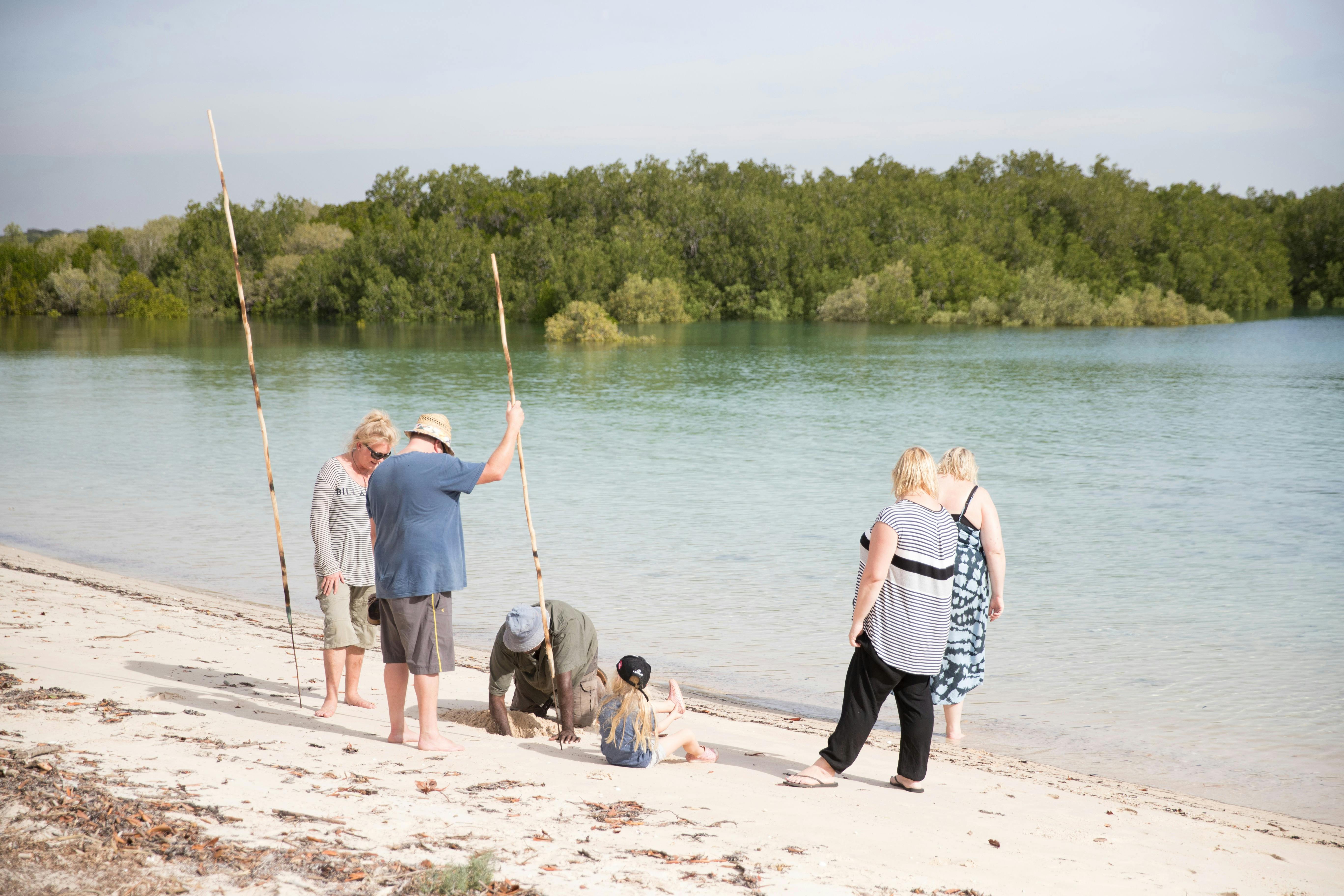 Tourist standing wiht spears on beach with Bundy.