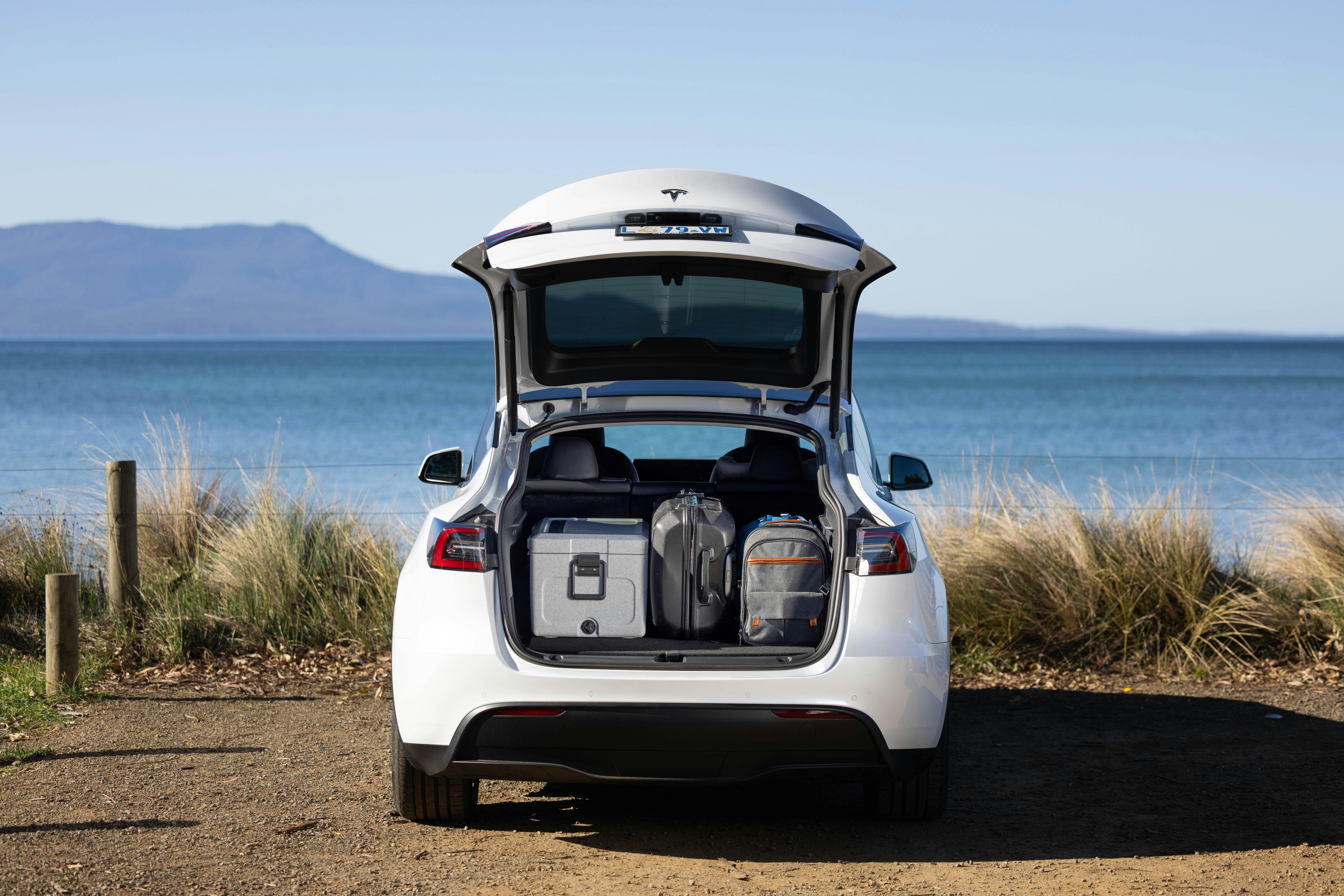 Electric Vehicle hire car (Tesla Model Y) parked at the beach in Orford Tasmania with trunk open.