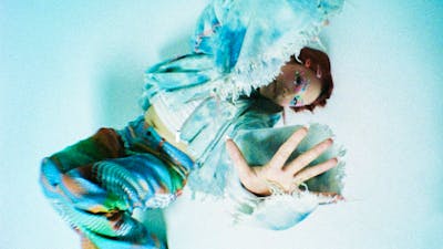 Performer posing on ground with her hand up to camera