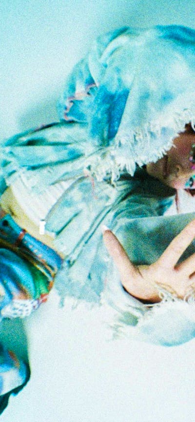 Performer posing on ground with her hand up to camera