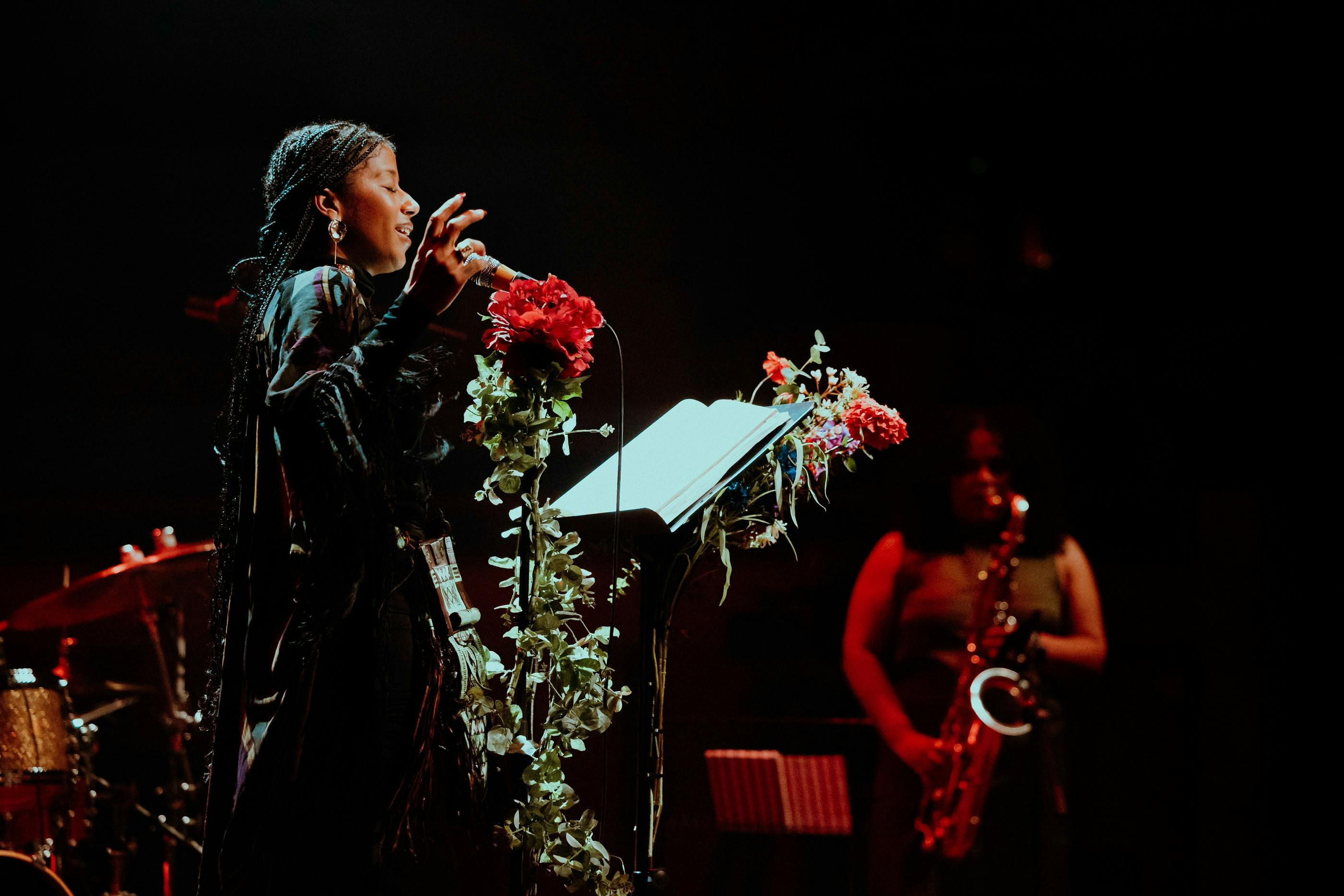 Woman performing live against a black background.
