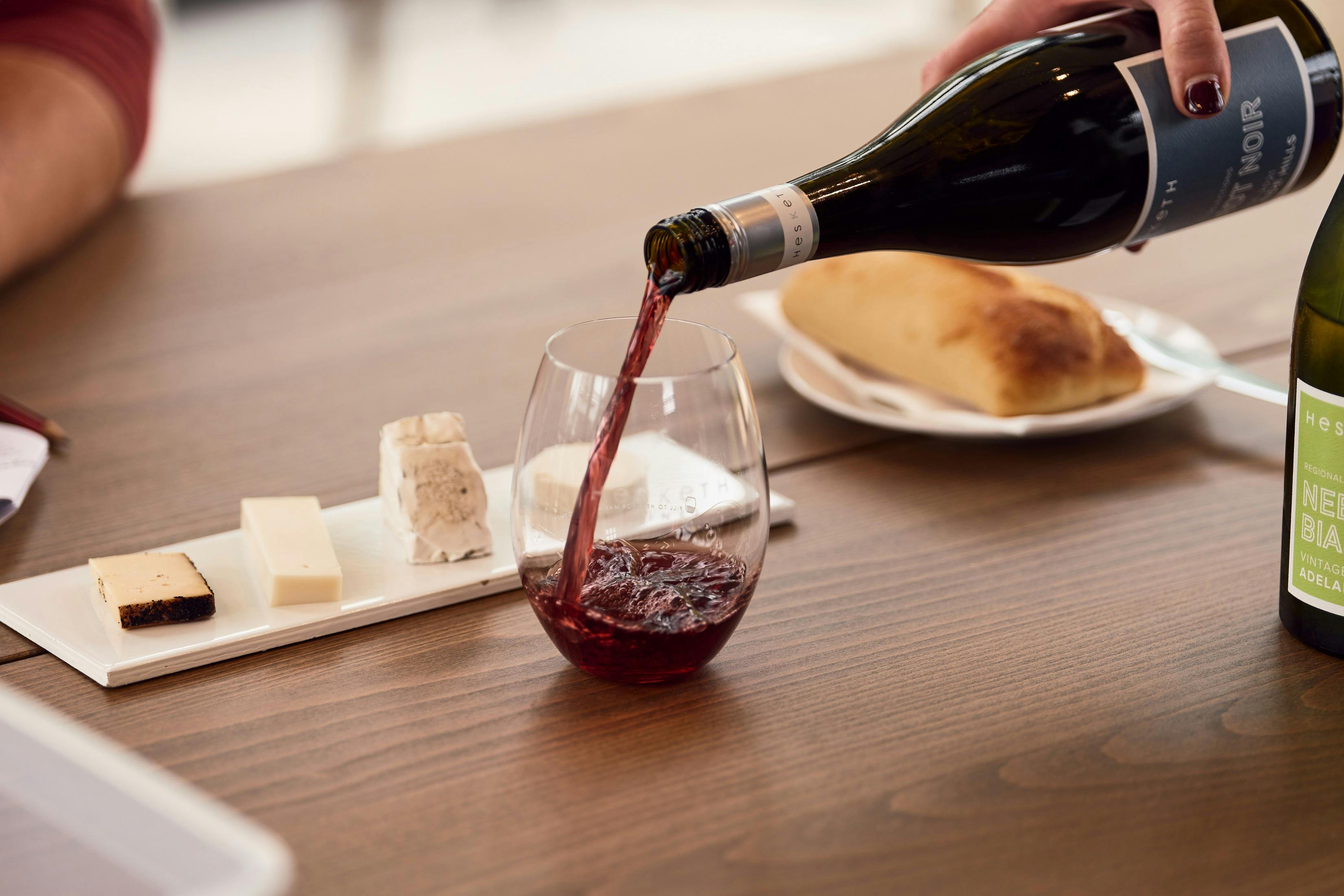 Cheese tile and wine being poured in a glass