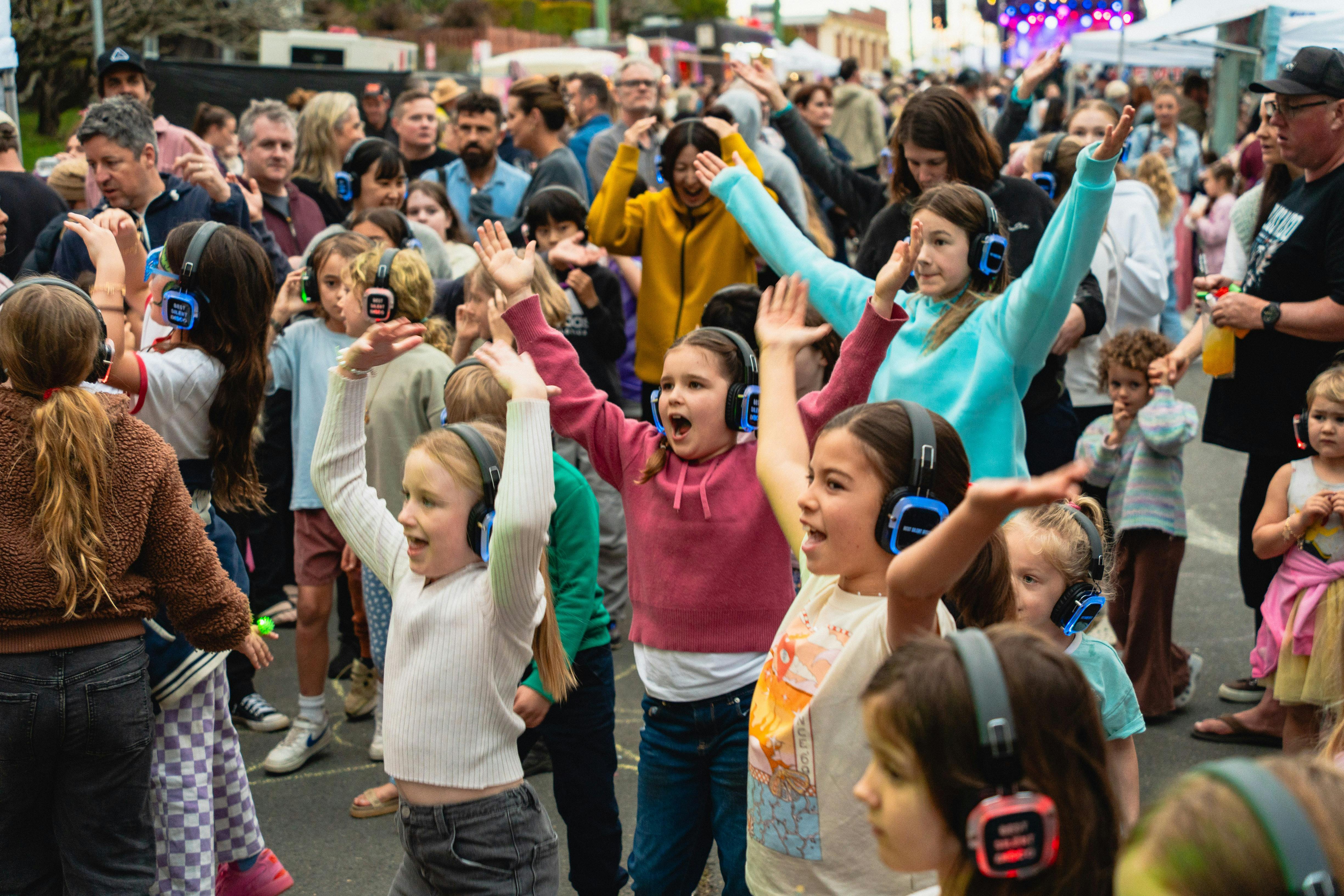 Children wearing headphones dancing at a silent disco.