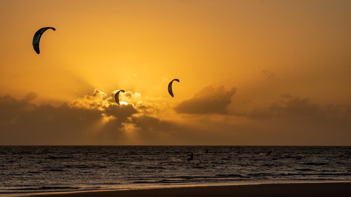 Three kitesurfers riding at sunrise time at Front Beach, Bowen