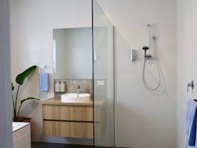Contemporary bathroom with walk-in shower, timber vanity and white tiled walls at Harolds on the Hil