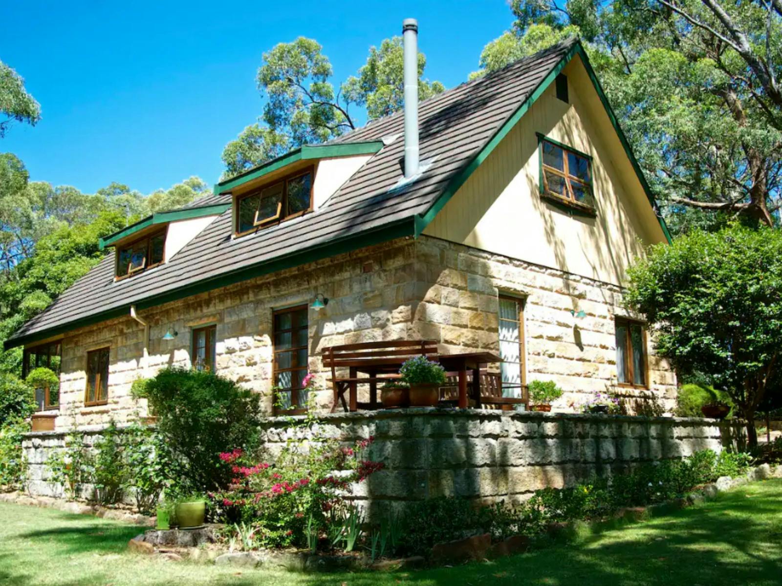 A sandstone house sits surrounded by bushland.
