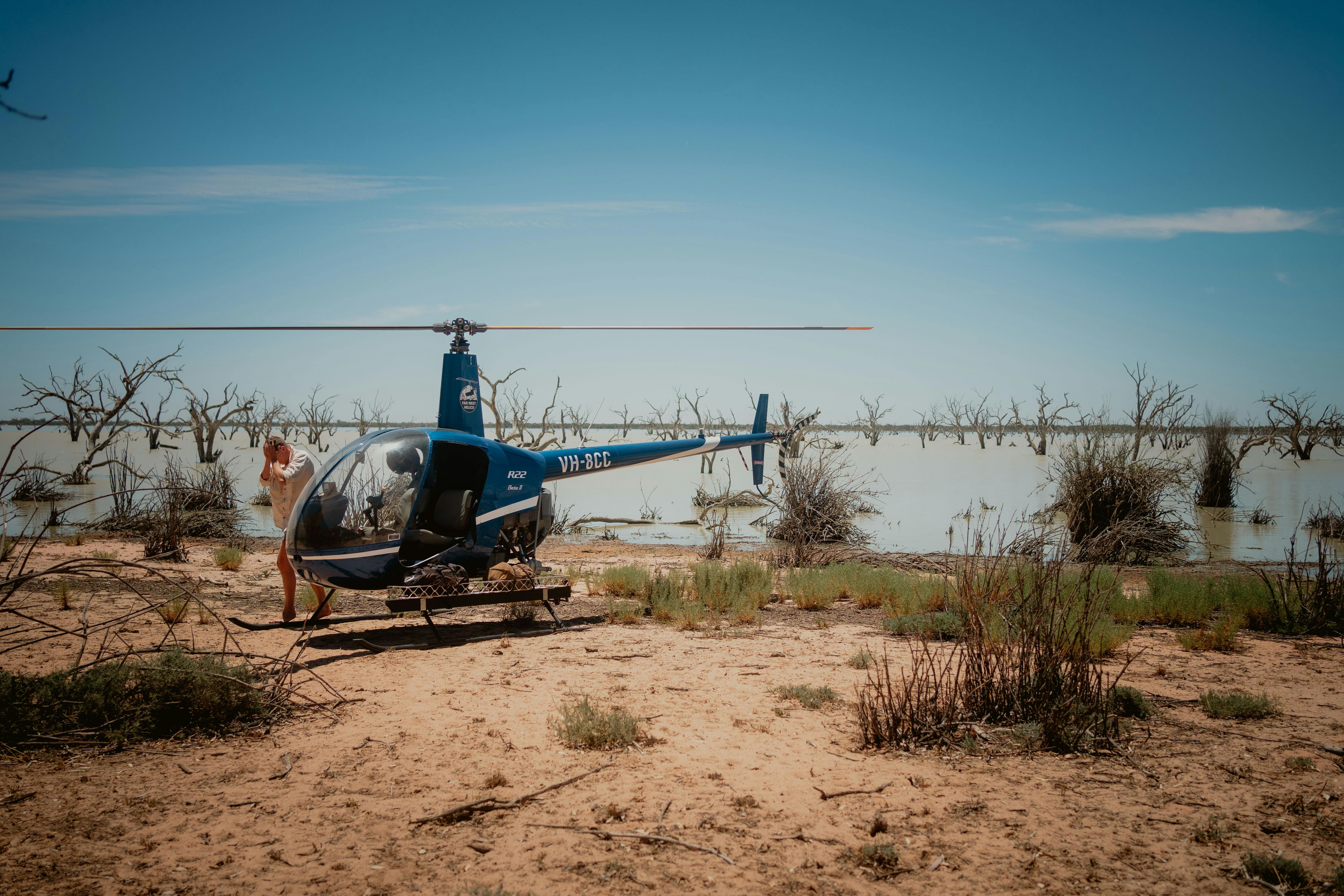 Blue helicopter landed with a lake in the background