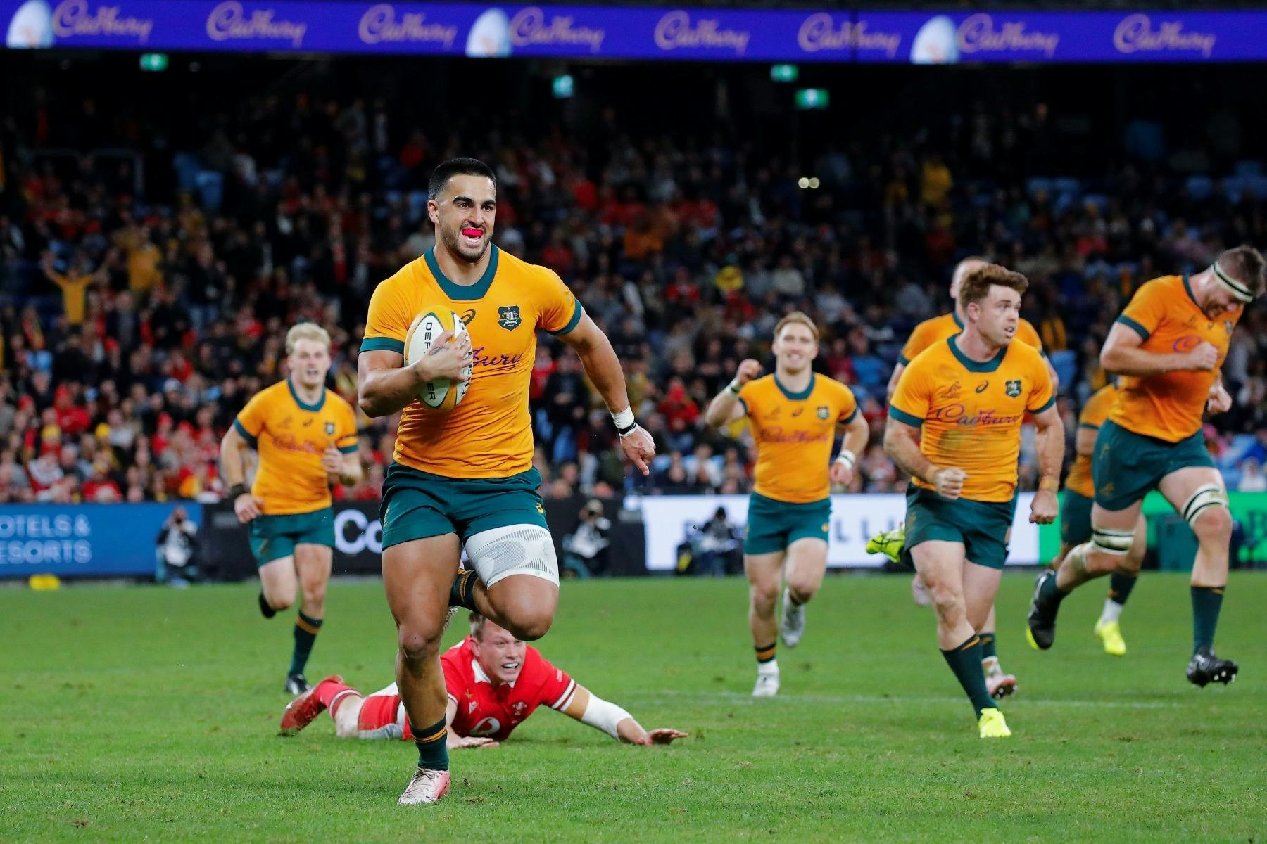 A group of rugby players on a field. One player is on the ground and  one player is running