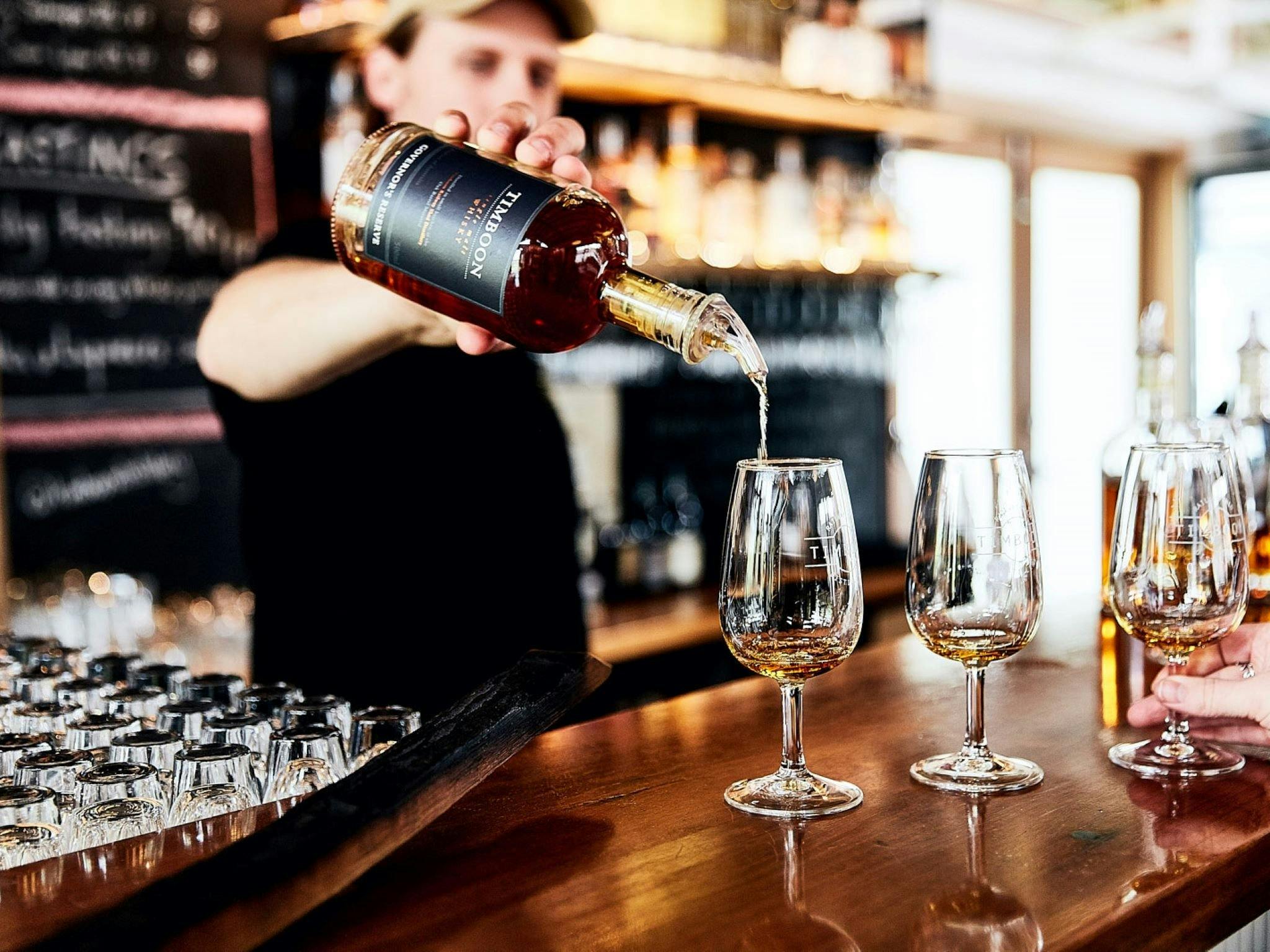 Bartender pouring whisky from a bottle into a tasting glass