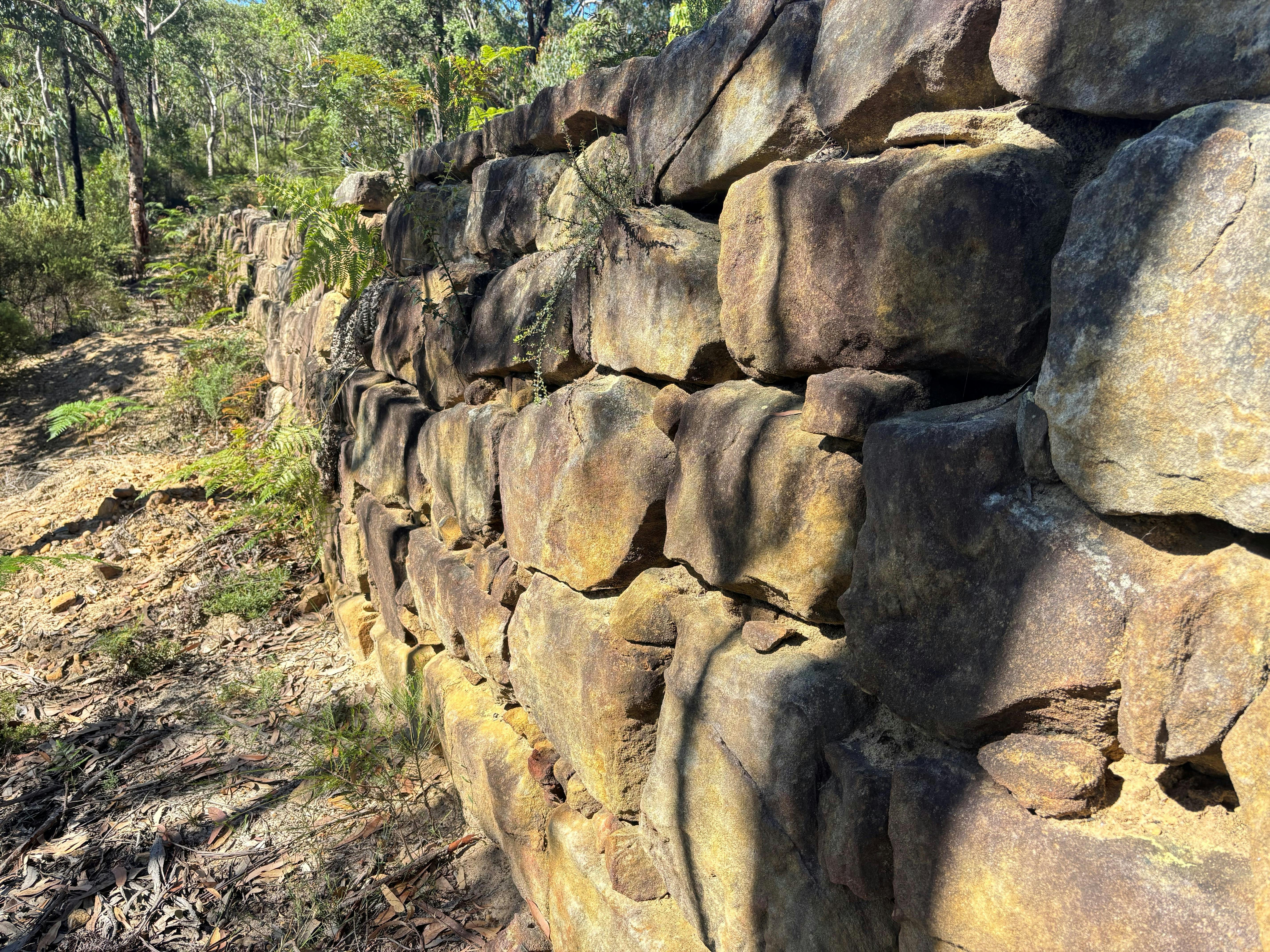 A dry stone wall or buttress supporting the edge of a road on the side of a gully.