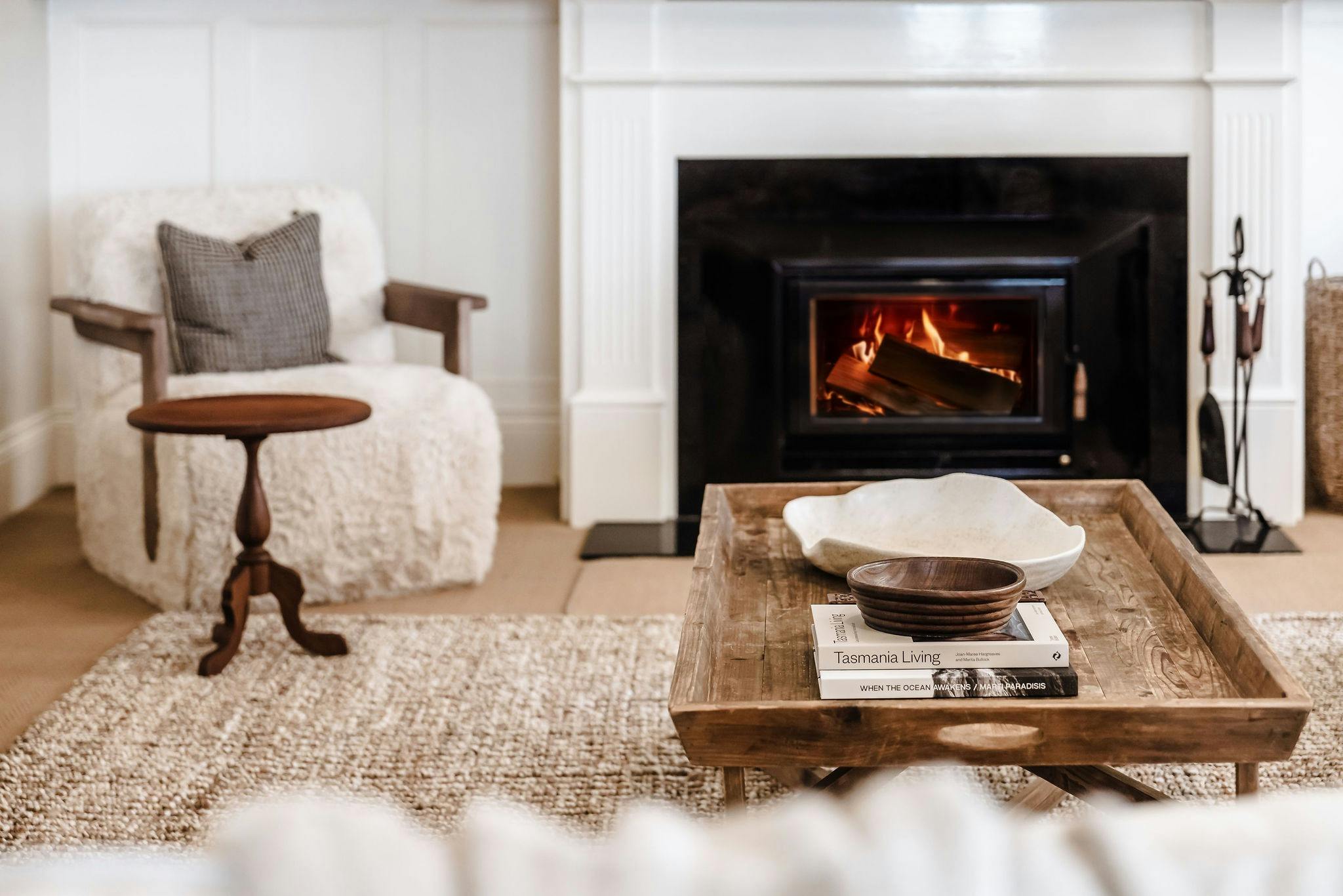 An image of a soft fluffy chair, the fire roaring and coffee table in the formal living room