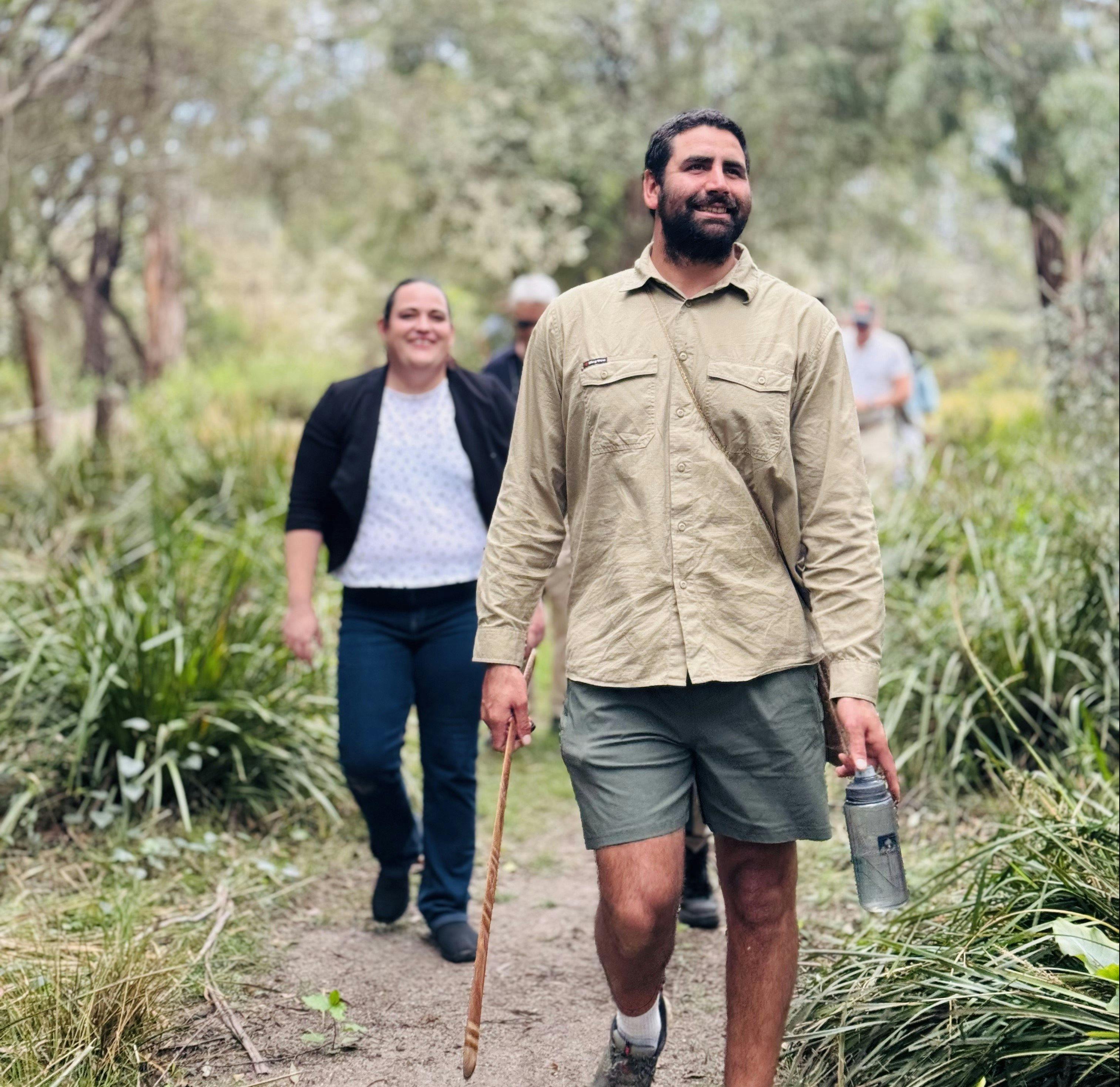 Nathan Lygon walking in front with boomerang in hand with tour participants following