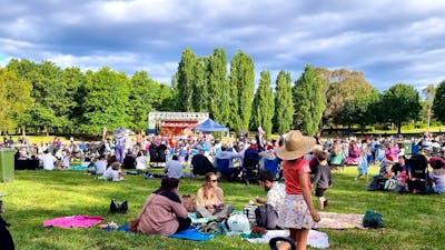 people sitting on a grass field watching Carols in Town Park Canberra