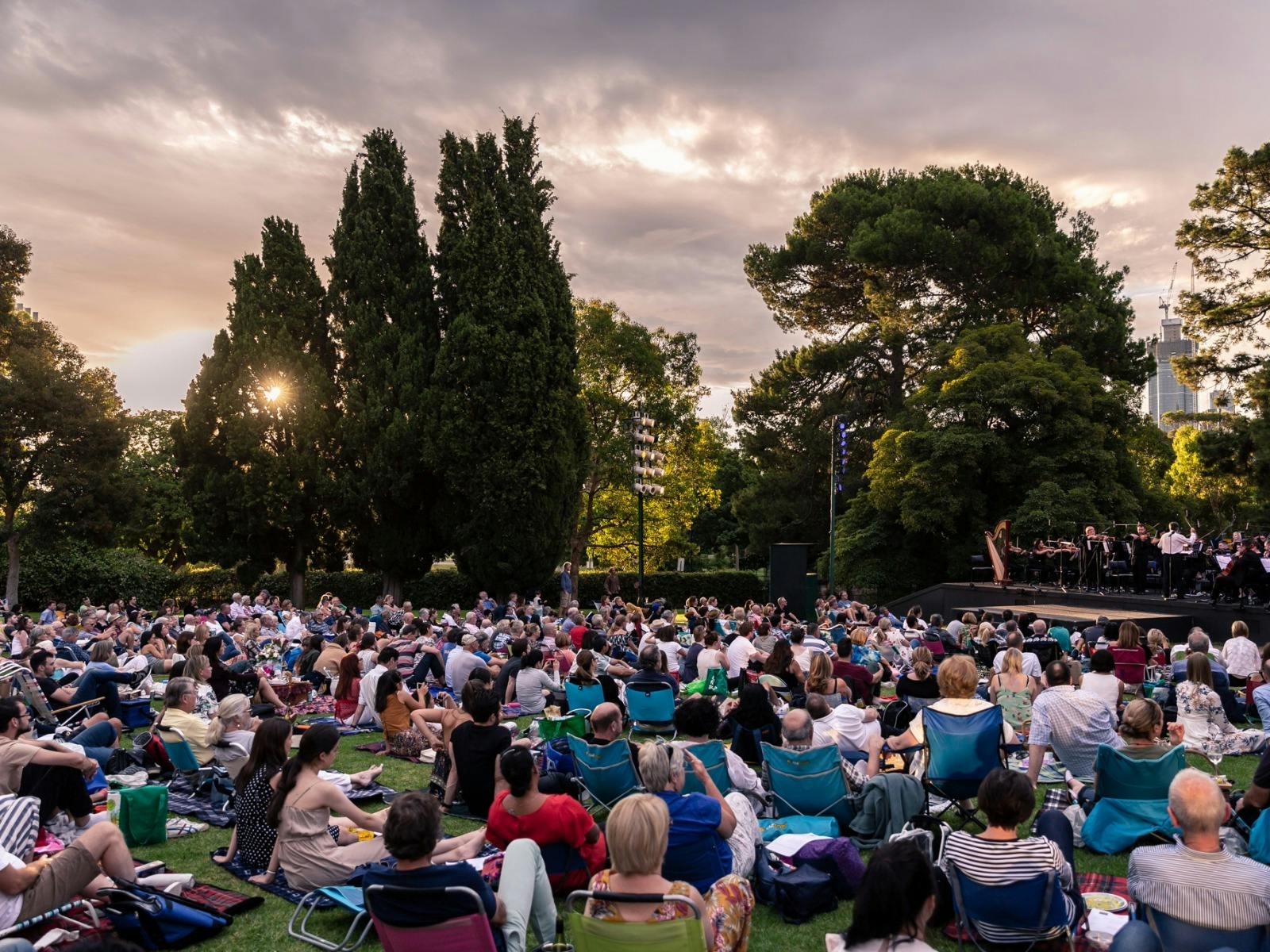 Audience seated picnic-style at Mozart by Moonlight, Royal Botanic Gardens, sunset.