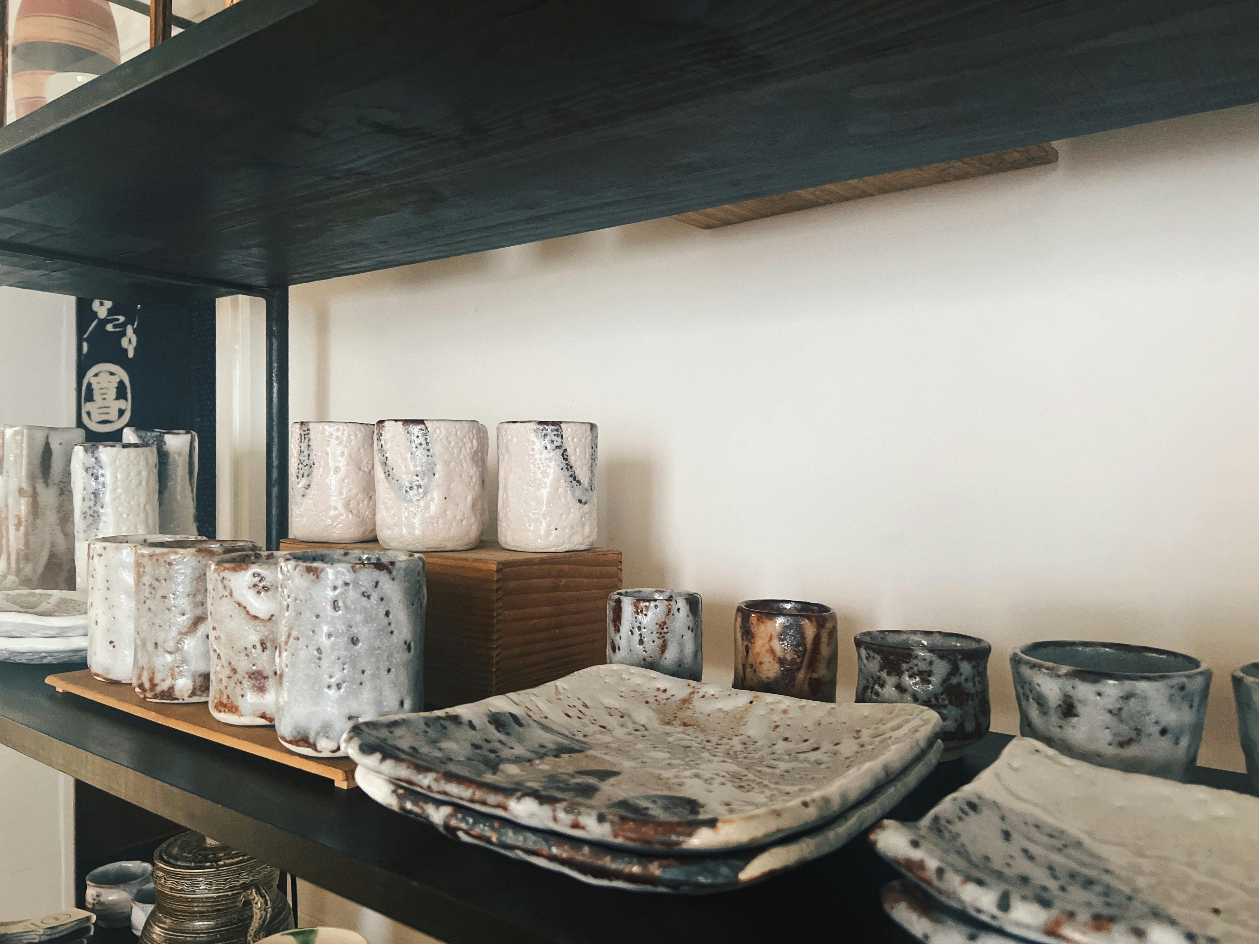 Highly textured ceramics with shino glaze are displayed on the shelves of the store