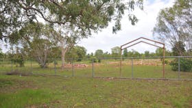Cemetery entrance marked by a steel portal structure that appears considerably older than the fence.